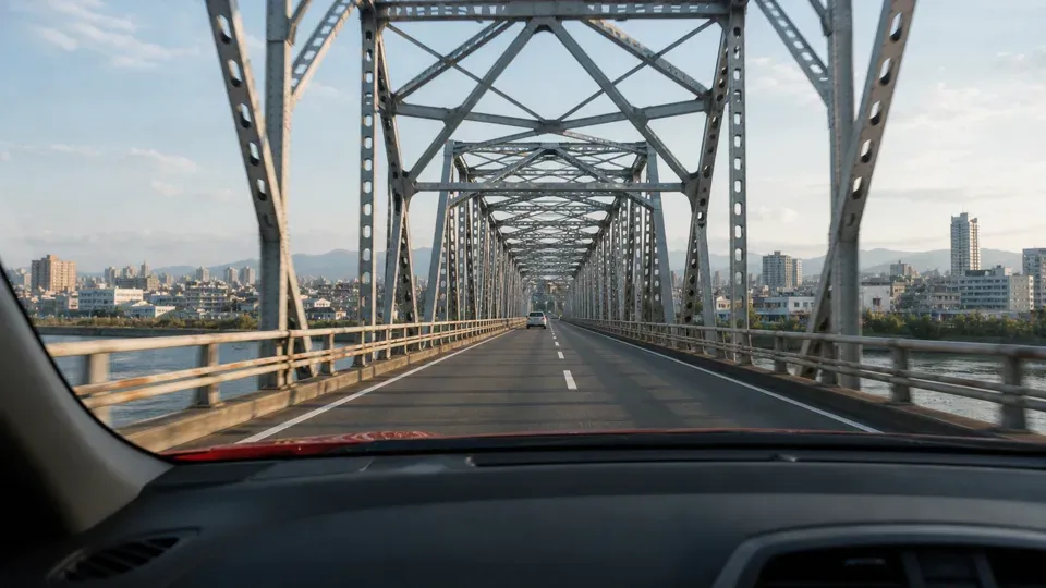 POV from inside a red car driving across an iron bridge